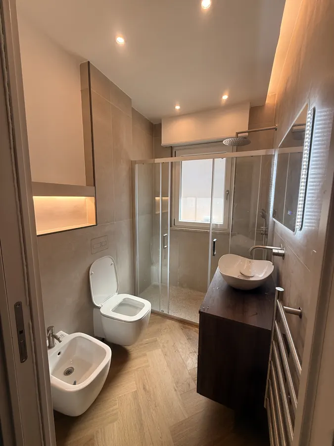 Bagno EdilEMI con doccia in vetro, lavabo da appoggio e pavimento color legno