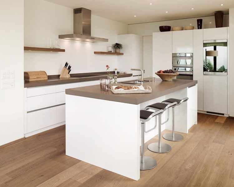Cucina bianca con isola centrale e pavimento in legno
